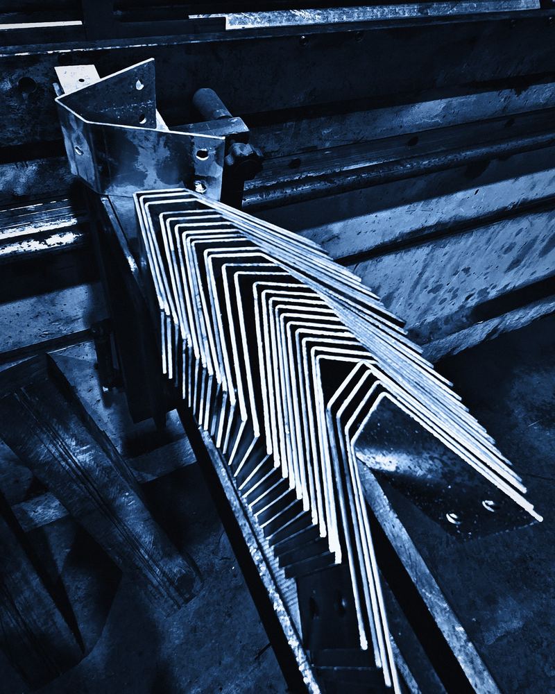 A fan of bent steel angles stacked at the press brake