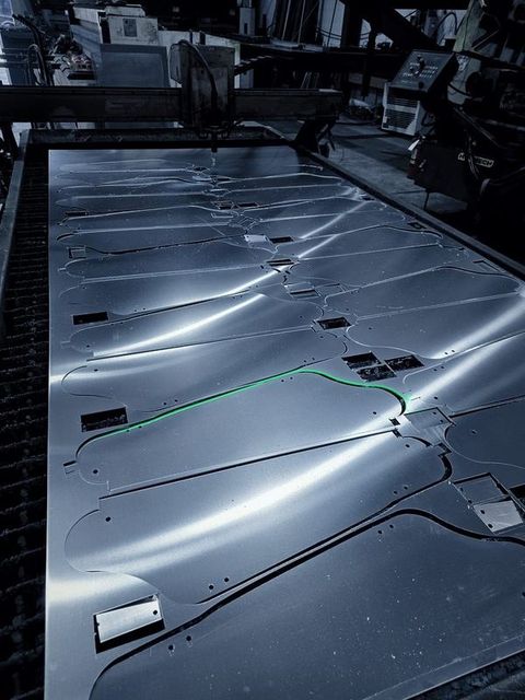 A sheet of metal on the cutting table with part outlines cut through it