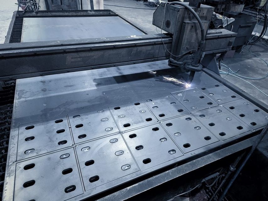 The torch cuts rows of slotted plates out of a steel sheet on the cutting table