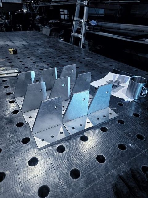 A group of bright gusset brackets standing on the fixture table