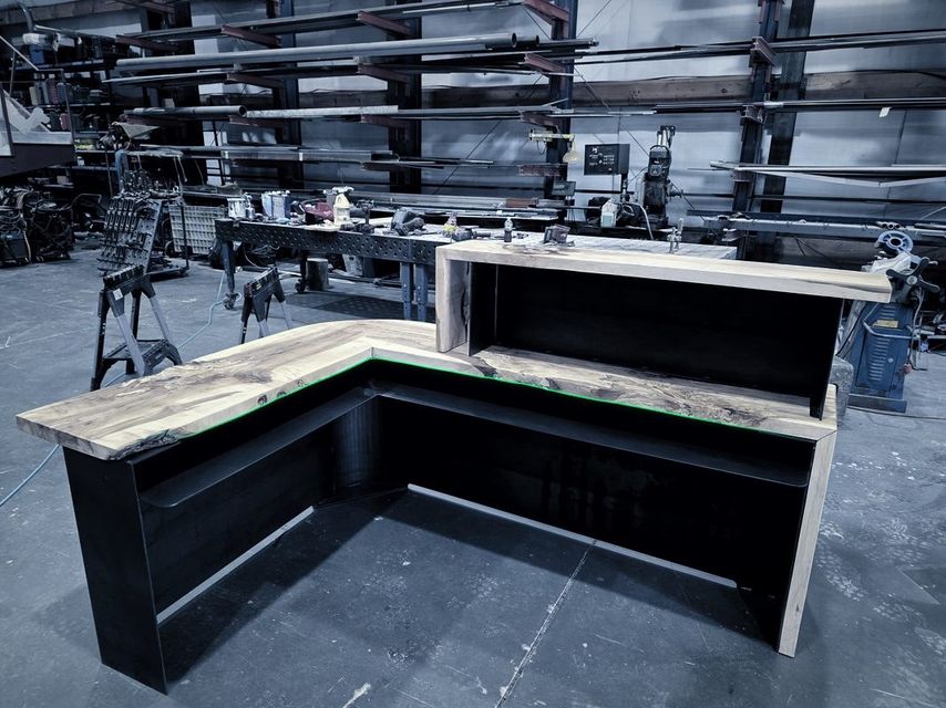 An L shaped counter with a black steel base and a live edge wood top on the shop floor