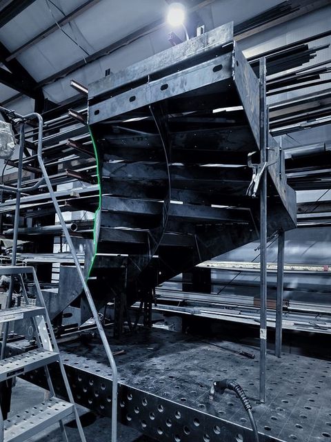 The underside of a curved steel stair standing on the fixture table