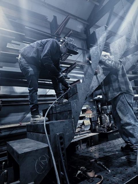 Two men work on a curved steel stair with sparks flying
