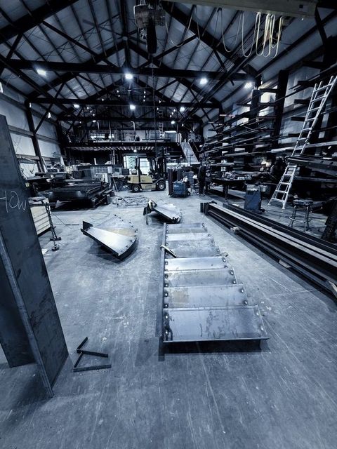 A steel stair section and a curved landing lying on the shop floor